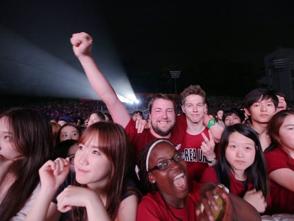 International students of Korea University cheering together at Ipselenti, wearing red KOREA UNIV. tees.